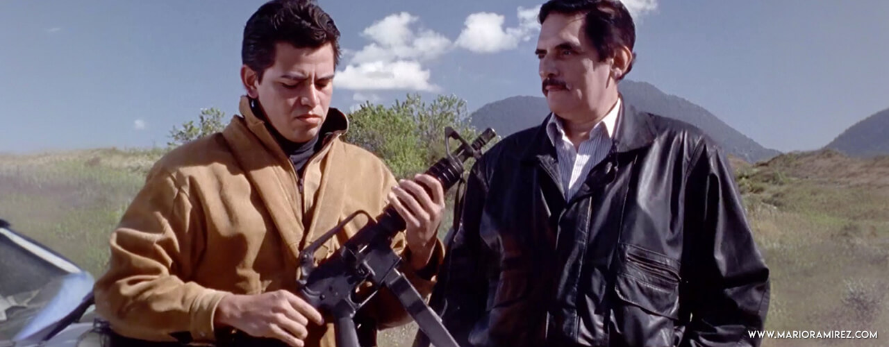 Mario Ramírez sostiene un rifle AK-47 mientras lo observa Manuel Ojeda